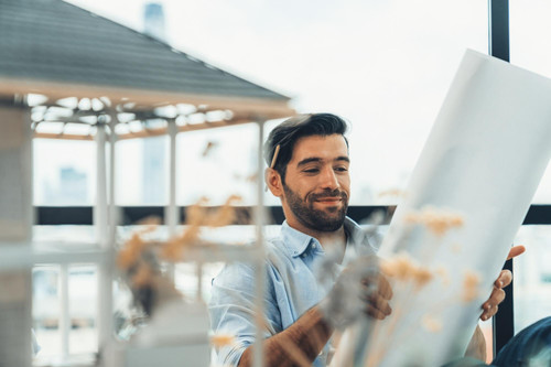 smiling engineer looking project plan while design house model modern office smart caucasian sitting.jpg