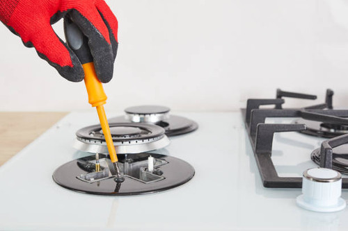 Repairs and fixing of gas control panel. Man hand in protective gloves repairs hotplate of a hob..jpg