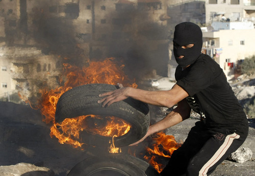A Palestinian youth holds a burning tyre during clashes in the East Jerusalem neighbourhood of Issaw