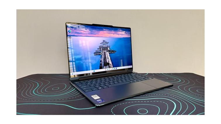 Lenovo Yoga 9i 2-in-1 Aura Edition laptop on a black desk pad with blue lines