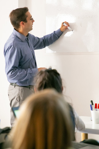 profesor concentrado dibujando bordo y explicando la leccion los alumnos.jpg