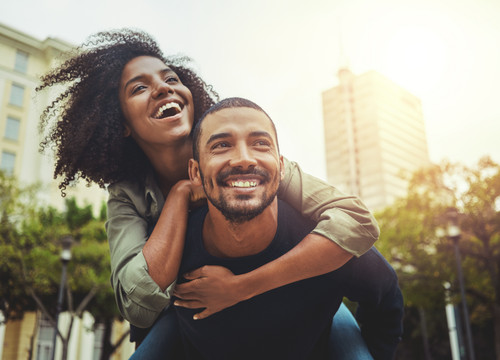 Cheerful young man giving piggyback ride to his girlfriend outdoors in the city.jpg