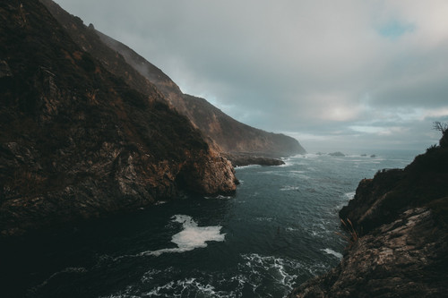 a body of water with rocks and a cliff.jpg