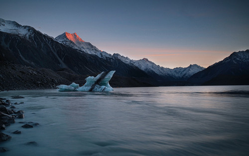 a iceberg in the water with mountains in the background.jpg