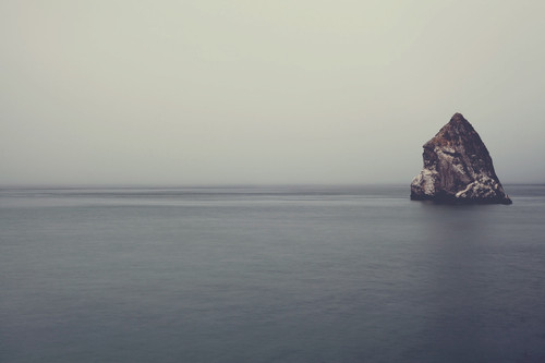 a large rock in the middle of a body of water.jpg