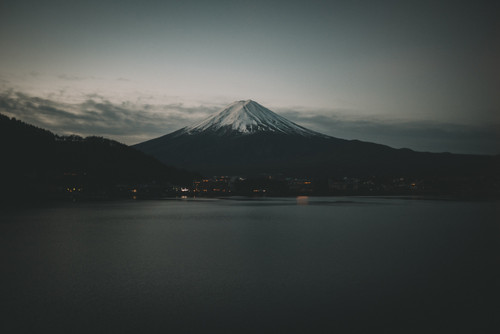 a mountain with snow on top and a body of water.jpg