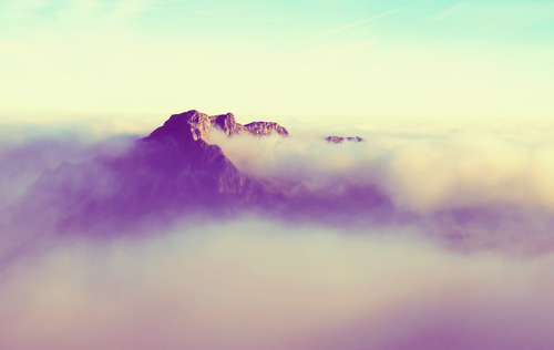 a mountain with clouds above it.png