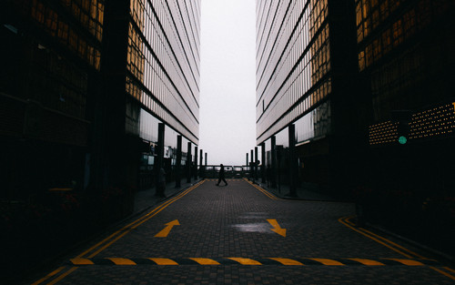 a person walking on a street between two tall buildings.jpg