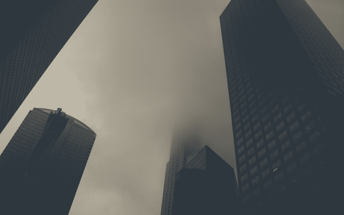 a group of tall buildings with clouds in the sky.png