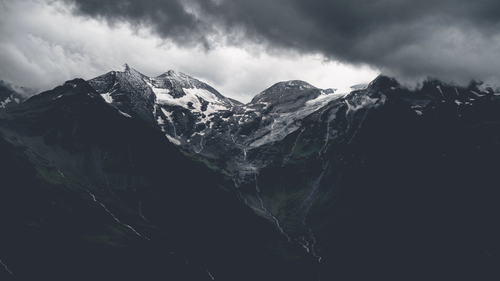 a snowy mountain tops with clouds in the background.png