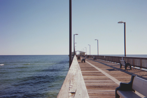a wooden walkway with benches and a body of water.jpg