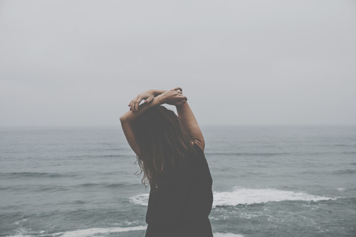 a woman standing on a beach with her hands up.jpg