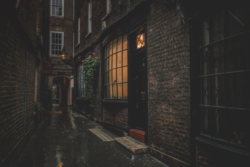a dark alleyway with a brick building and a window.jpg