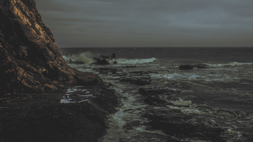 a rocky beach with waves crashing on the shore.png