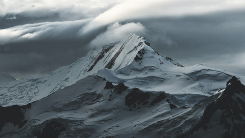 a snowy mountain with clouds above.jpg