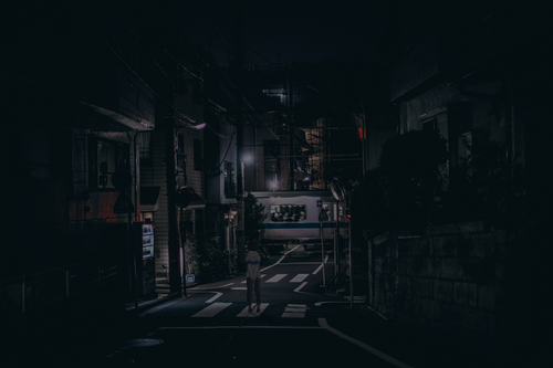 a person standing on a street at night.png