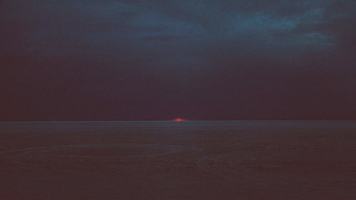 a sunset over a body of water with Marfa lights in the background.png