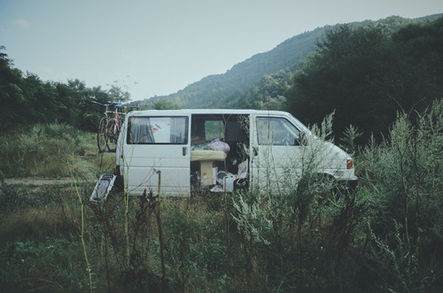 a van in a field with a bicycle and a mountain in the background.jpg