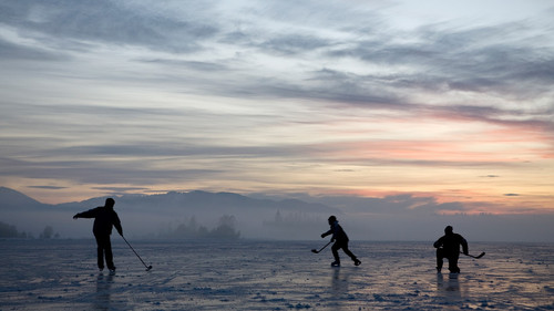 Silhouettes of kids playing hockey on frozen lake at sunset, Kirchsee, Bavaria, Germany 1080p