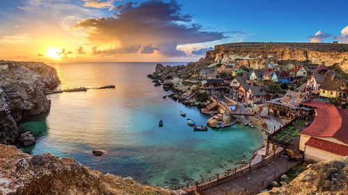 The famous Popeye Village in Anchor Bay at sunset with clouds, il Mellieħa, Malta 1080p