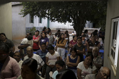 Relatives and neighbors of Evarado Ventura Hernandez pray in front of an improvised altar with his p.jpg