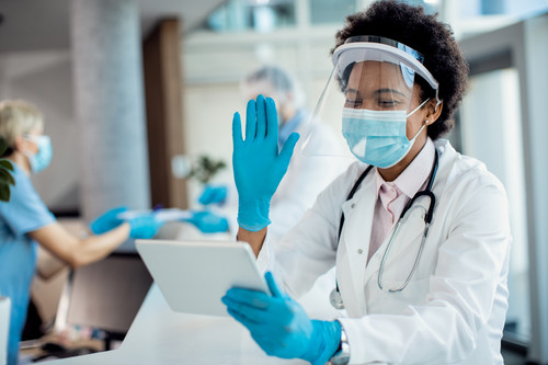 Black female doctor having video call over touchpad and greeting someone while working at medical cl.jpg