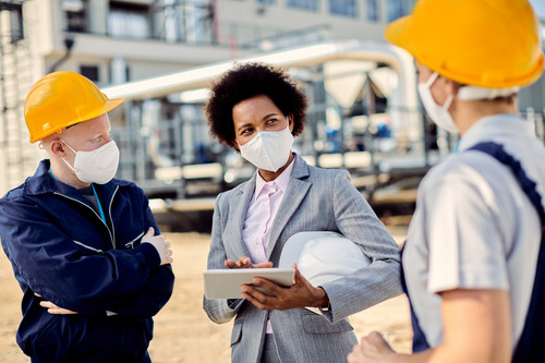 Black businesswoman and two construction workers wearing protective face masks while talking about o.jpg