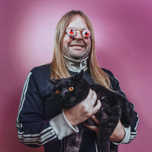 Man with long hair and eyes popped out holding black cat.jpg