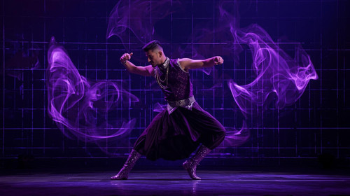 An Indian dance icon wearing a sleeveless purple vest and metallic violet boots performs a high ener.jpg