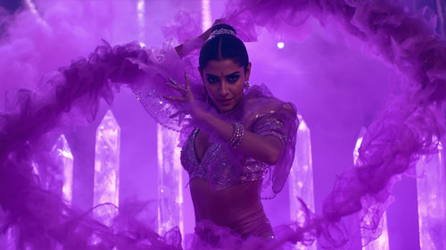 A bold Indian actress dancer performs in a shiny purple holographic outfit as violet fog swirls arou.jpg
