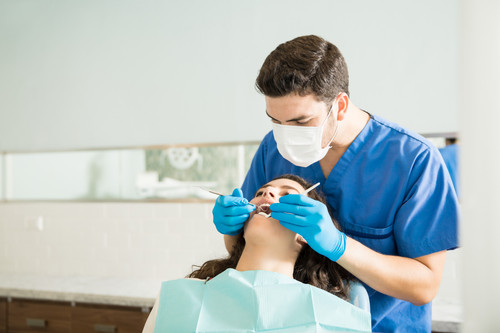 male dentist examining young woman with dental carver medical clinic.jpg