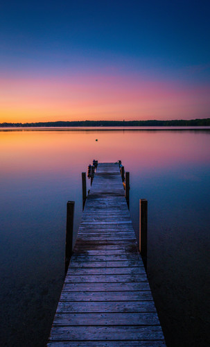 bela foto das cores por sol no horizonte de um lago tranquilo com uma doca.jpg