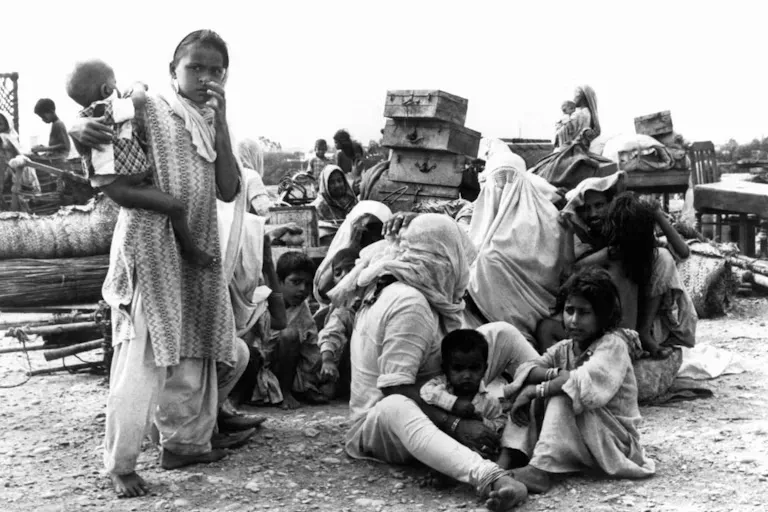 عائلات لاجئة منهكة جالسة على الأرض مع متعلقاتها بعد الفرار من العنف أثناء تقسيم الهند عام 1947