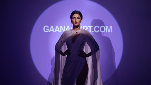 A mysterious Bollywood diva wearing a dramatic white cape dress stands with a spotlight behind her, .jpg