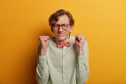Ecstatic male nerd raises clenched fists, believes in success, closes eyes and awaits announcement o.jpg