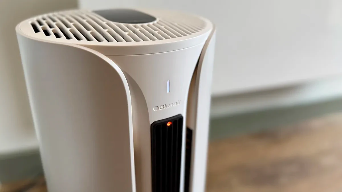 A photo of the Blueair T20i Air Purifier with its remote in a room with white walls and laminated wooden floors