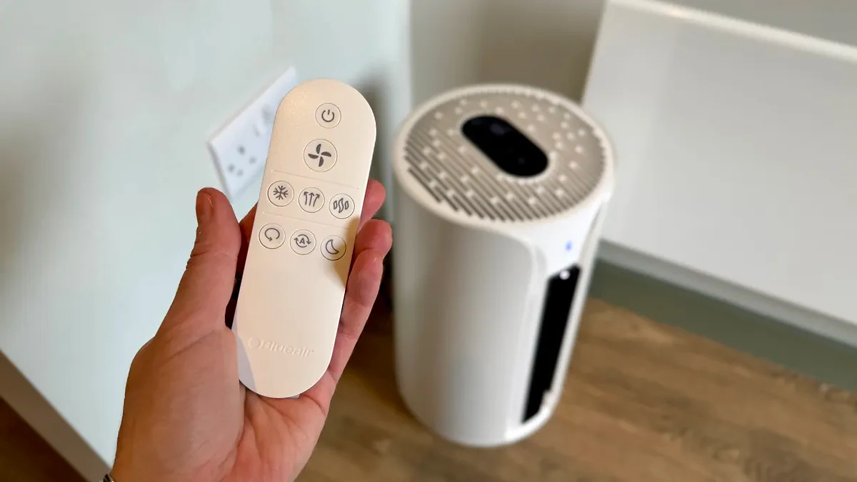 A photo of the Blueair T20i Air Purifier with its remote in a room with white walls and laminated wooden floors
