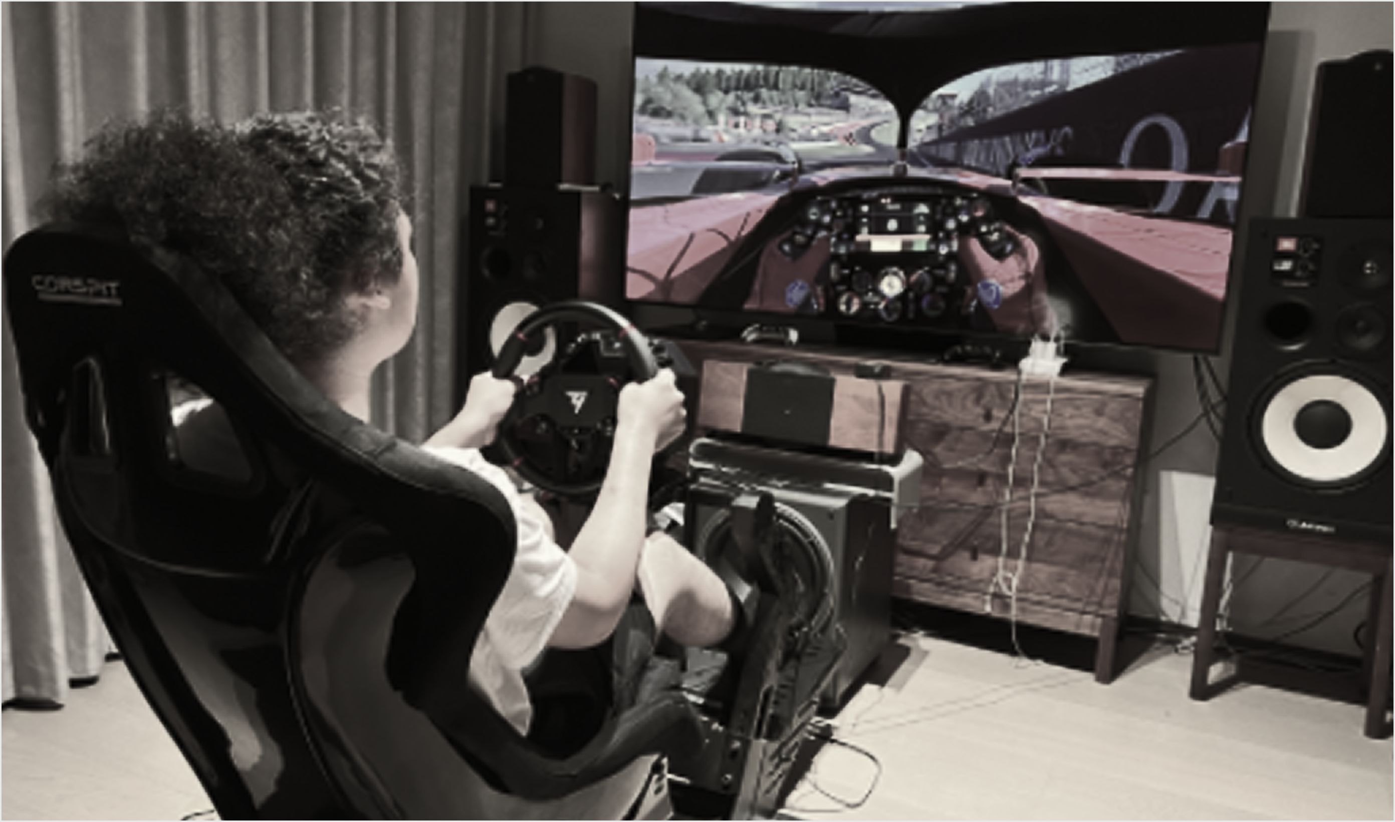 Over-the-shoulder view of a home sim-racing rig facing a first-person racing game