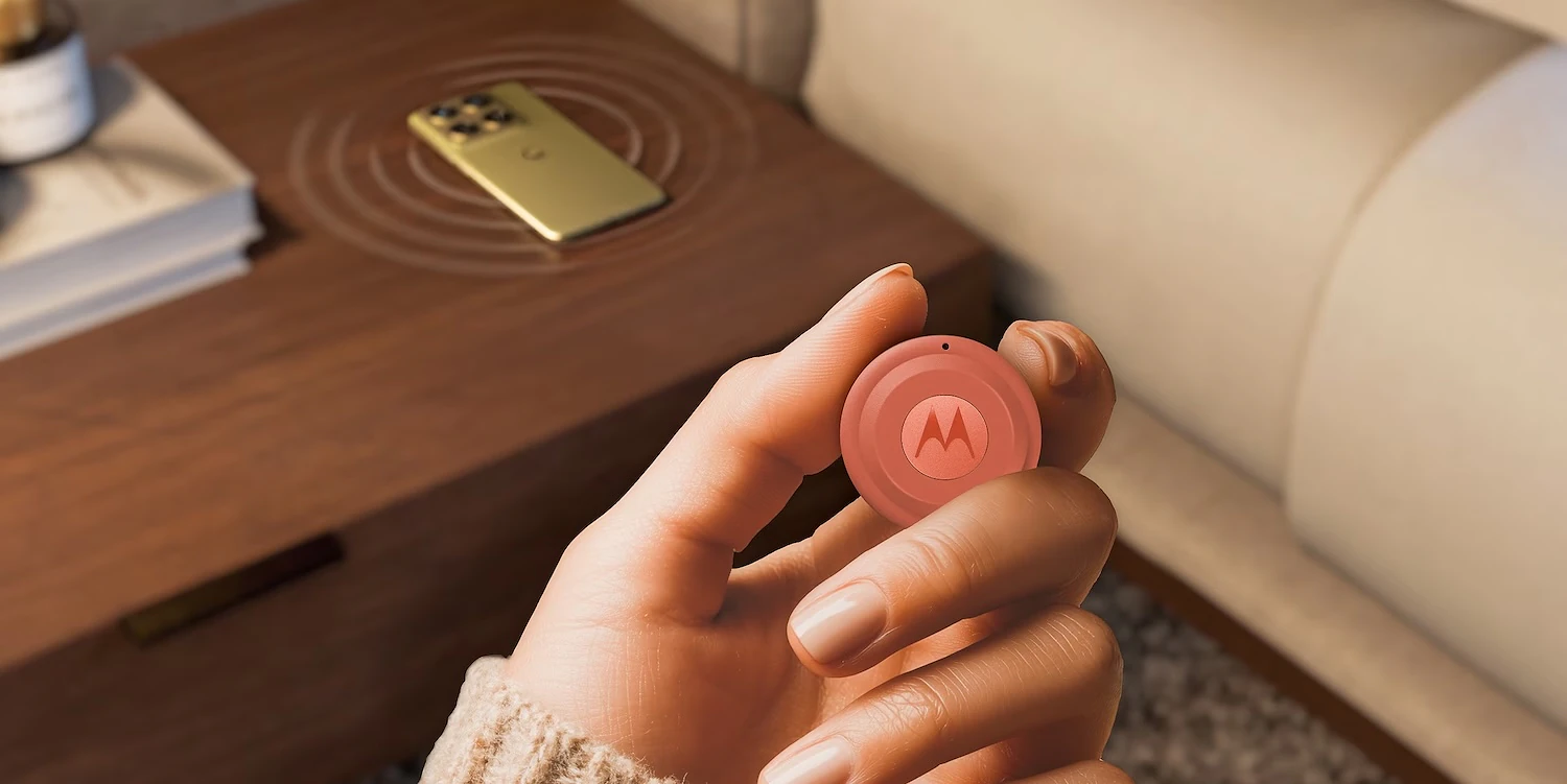 A hand holding a small pink device