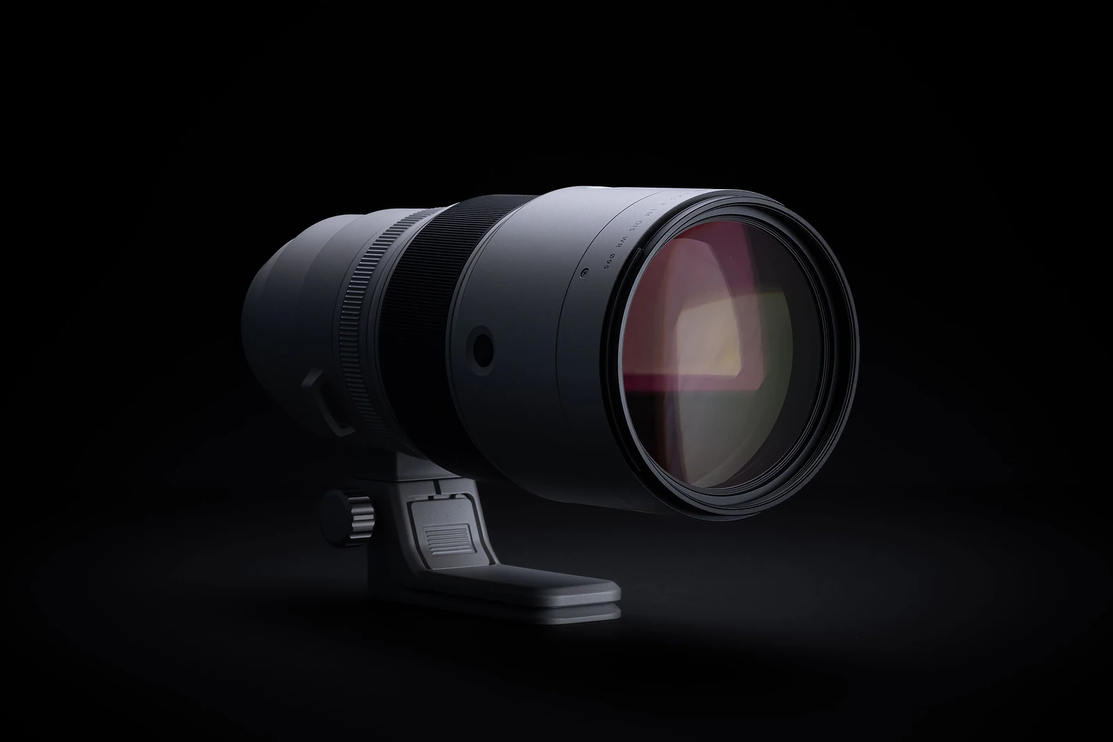 A telephoto camera lens with a tripod mount sits against a solid black background.