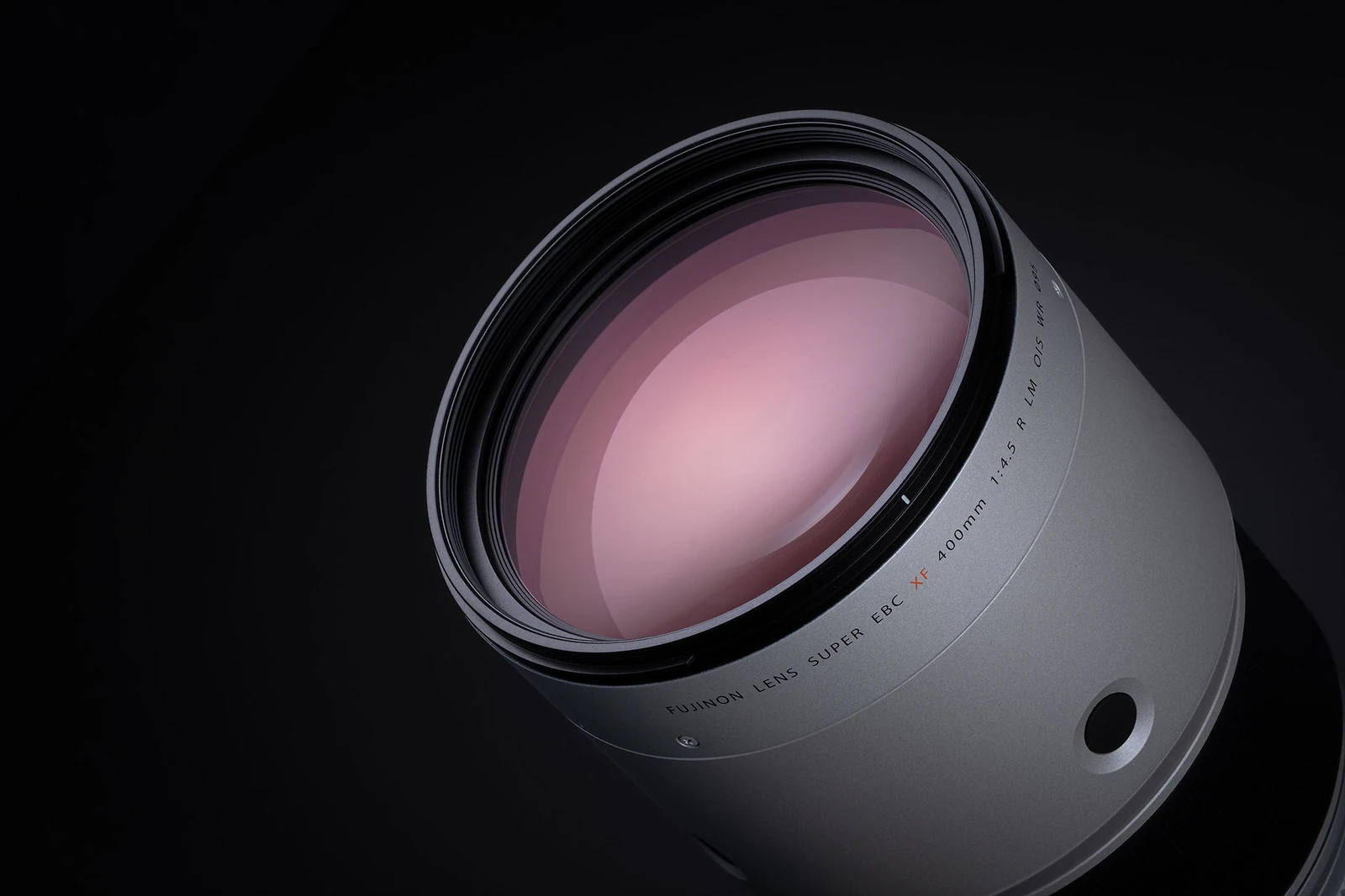 A close-up, angled view of a silver camera lens against a black background, with text on the barrel reading "FUJINON LENS SUPER EBC XF 400mm 1:4.5 R LM OIS WR".