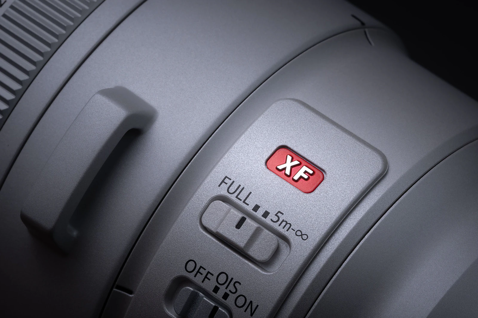 A close-up of a camera lens barrel featuring a red XF logo, a focus limiter switch set to FULL, and an Optical Image Stabilization (OIS) switch.