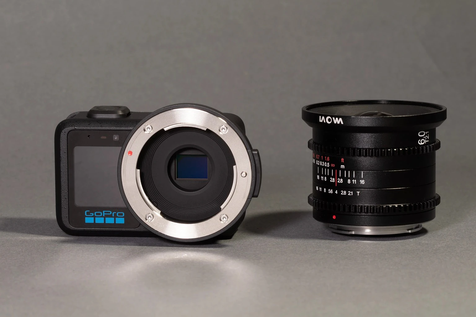 The GoPro Mission 1 Pro ILS with its lens mount and sensor facing the camera. Beside it is a small Laowa cinema lens.