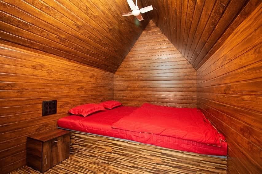 Cosy wooden A-frame room with a red double bed