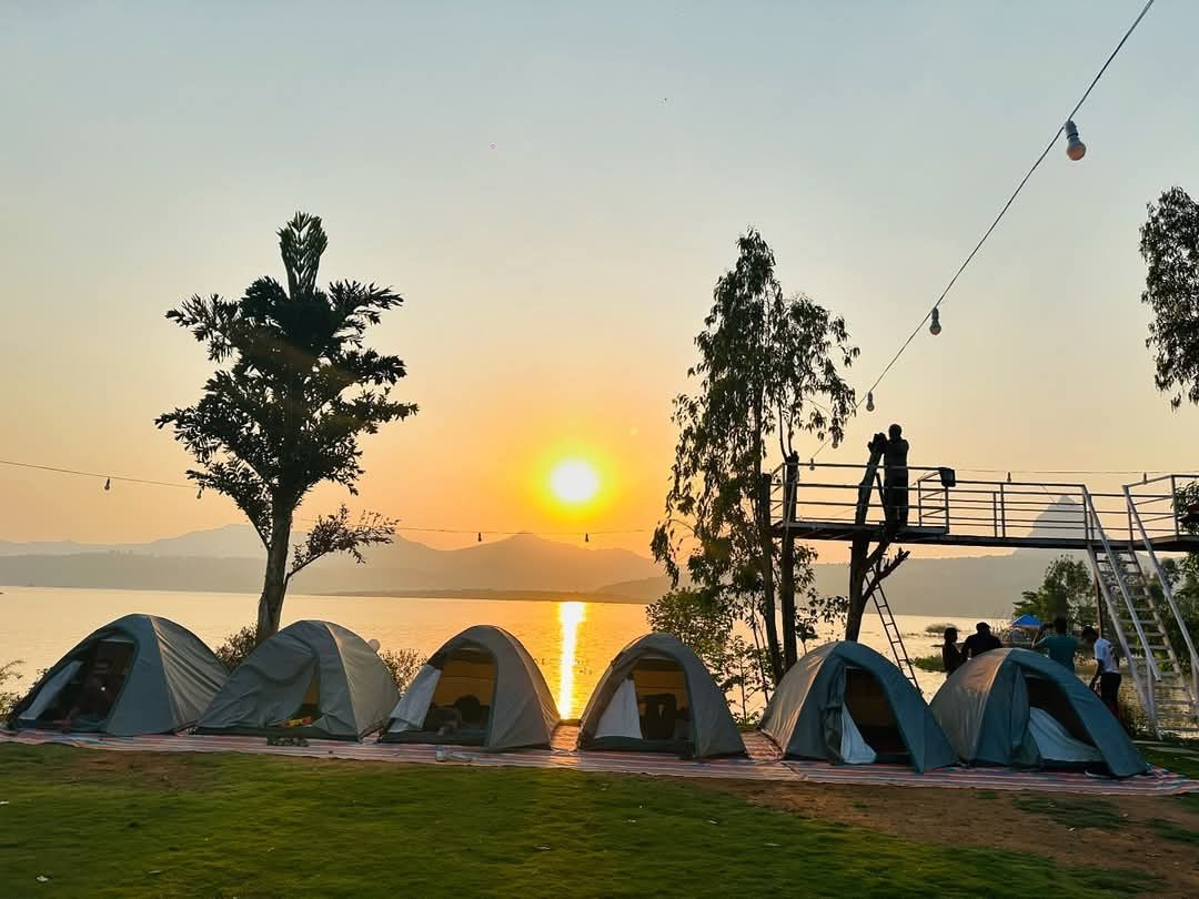 Sunset over Pawna Lake behind our lakeside dome tents and wooden watch deck