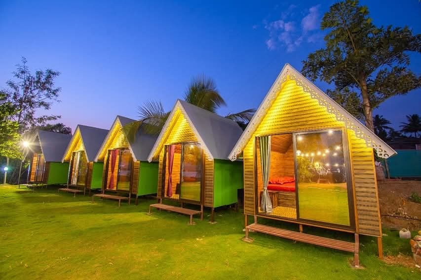 A-frame triangle cottages glowing warm yellow at dusk with string lights