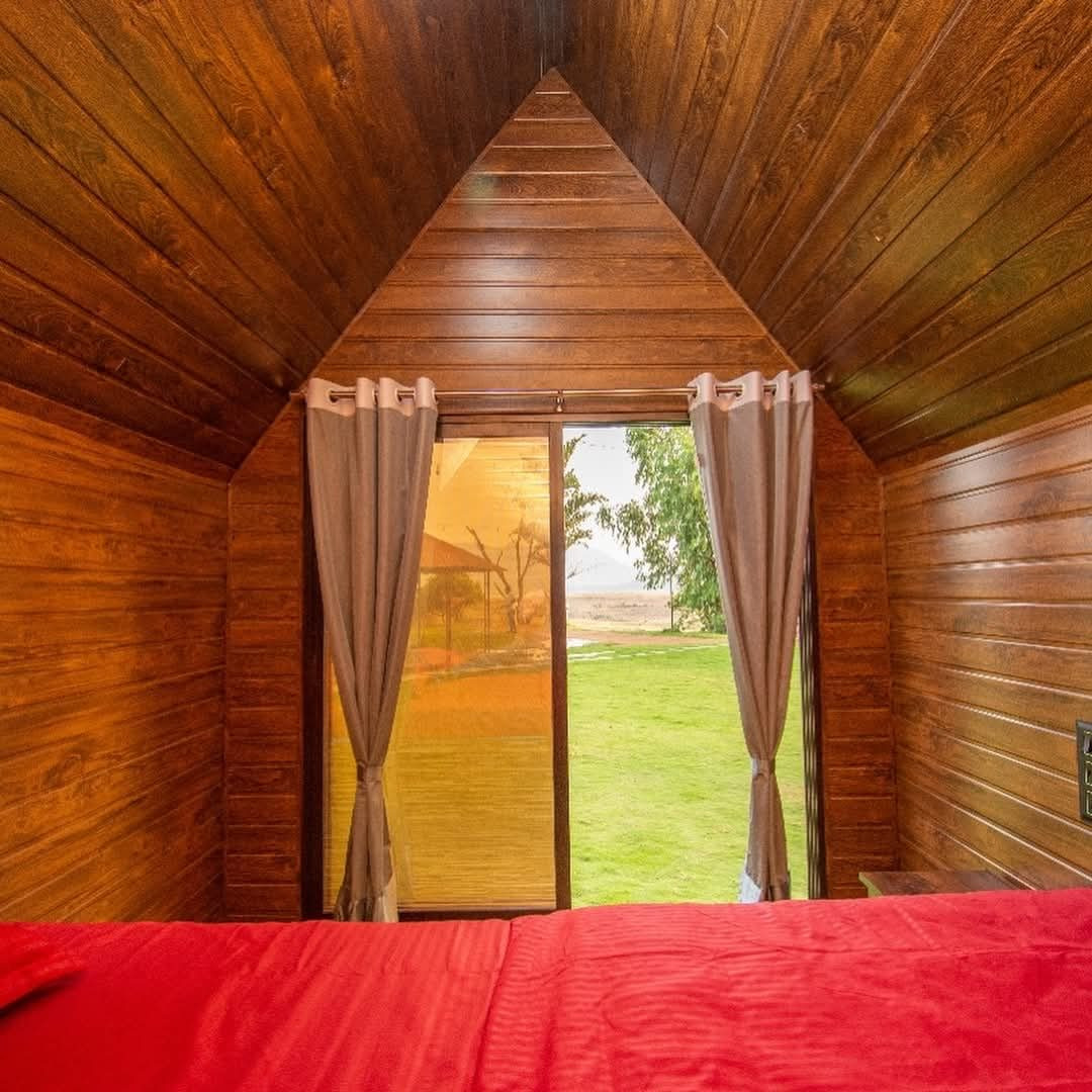 Wood-panelled cottage room with a double bed and a glass door opening to the lawn