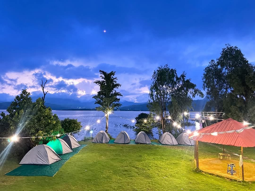 Lakeside tents and string lights at blue hour beside Pawna Lake