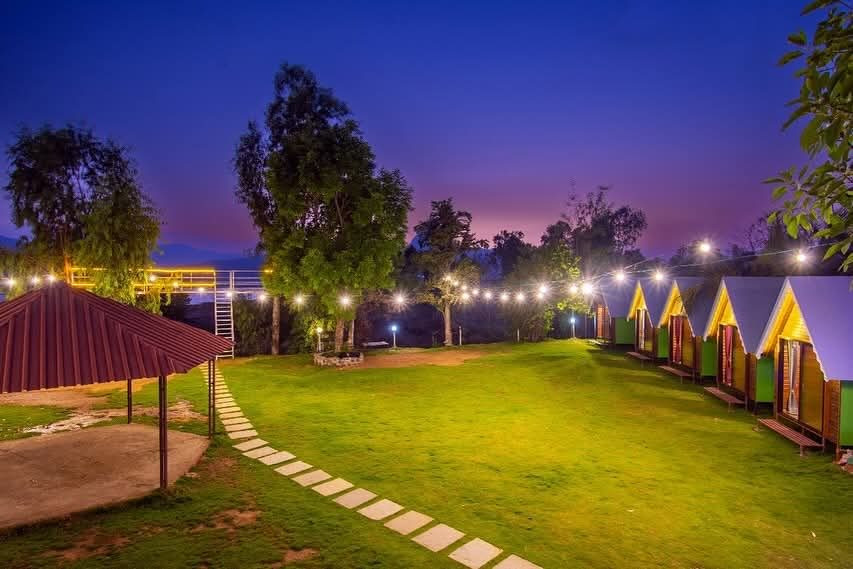 Pawna Lake camping in monsoon, lawn path and cottages at dusk at the campsite