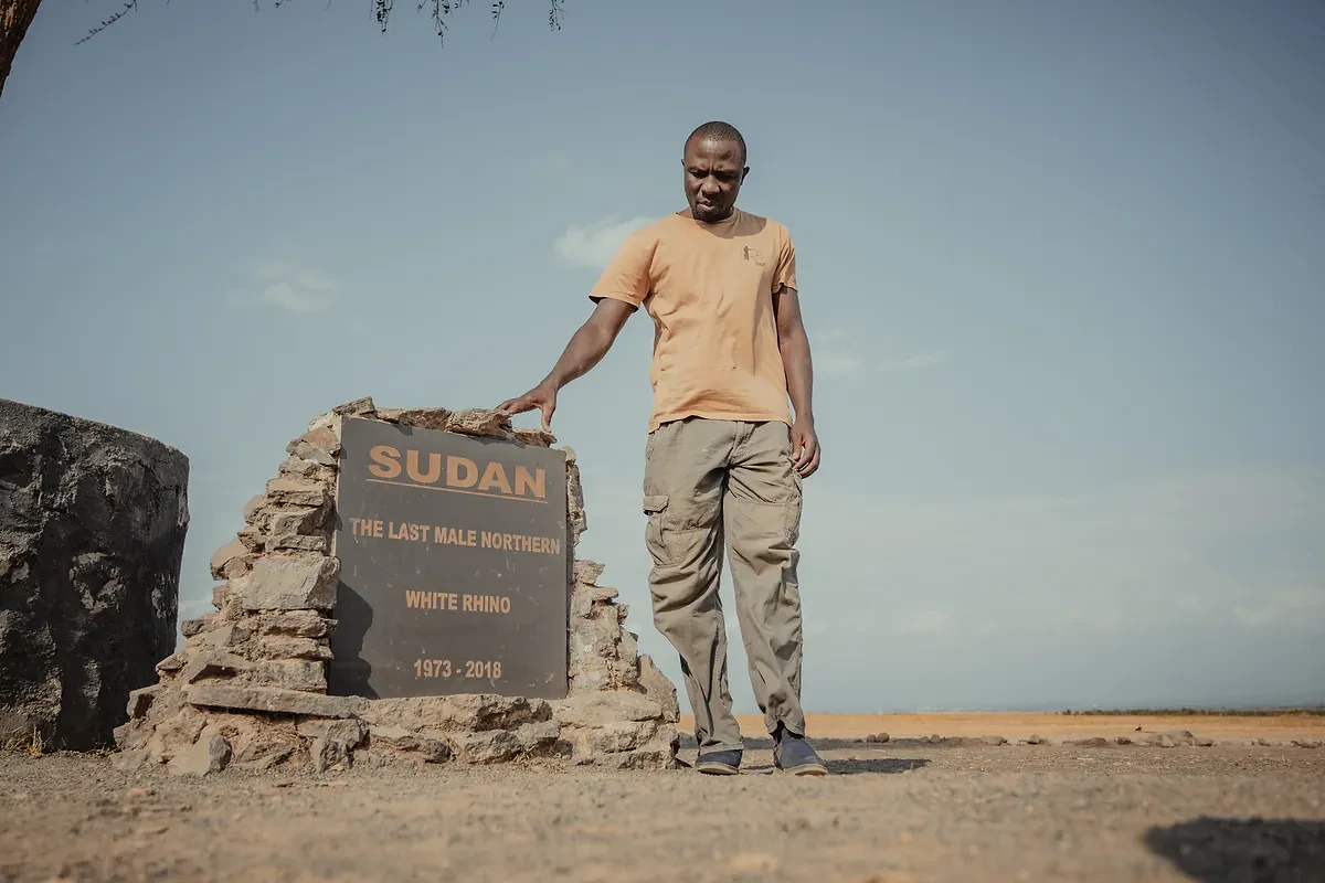 man beside the "Sudan, the last male northern white rhino" memorial